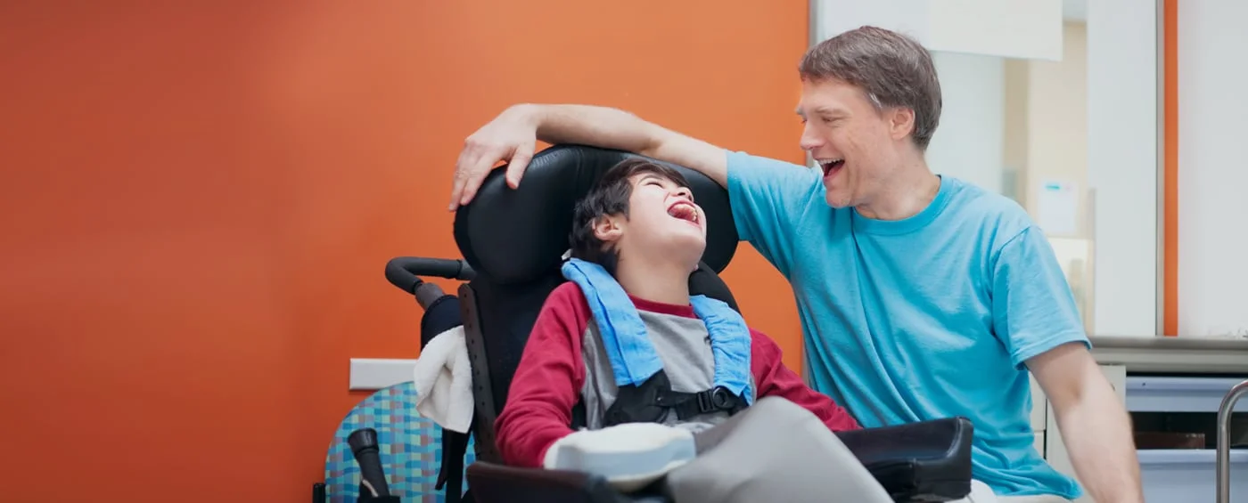 Uma criança sorrindo com um dos pais durante a reabilitação com células-tronco